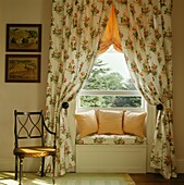 Floral gemusterte Vorhänge passend zur Fensterbank in einem Raum mit Stuhl und Kunstwerk