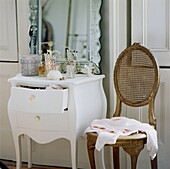 Pink blouse on antique chair beside bedroom dressing table with engraved mirror and open drawer