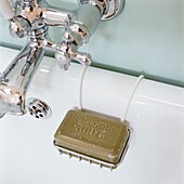 Soap in rack hanging next to silver bathroom taps