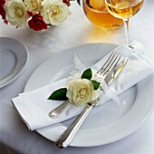 Single rose with cutlery and napkin on place setting