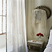 Lace top hanging on oval mirror in bedroom with net curtains