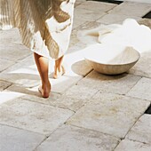 Low section of woman walking on stone floor with bowl