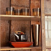 Nahaufnahme von glasiertem Geschirr und dekorativen Gläsern im orientalischen Stil, die in einem Holzschrank ausgestellt sind