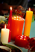 Table decorated with lit red and orange candles
