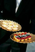 waiter serving dessert canapes and fruit tartlets