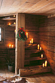 Lighted candles and Christmas spruce sprig on wooden staircase in wooden chalet