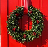 Red Panel door with festive wreath made from holly and evergreen foliage