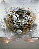 Frosted winter wreath with baubles and lit candles