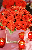 Red roses and lit tealights on table at Christmas in UK home