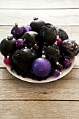 Large assortment of pretty christmas tree decorations in a dish on a tabletop