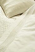 Crisp white stitched and lace bed linen on a bed