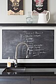 Shopping list on blackboard at sink with hose attachment in contemporary London home   UK
