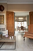 Sessel und Couchtisch mit Blick durch restaurierte Doppeltüren zum Esszimmer in einem Londoner Haus UK