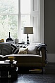 Black and white patterned lampshade and cushion fabric on sofa in front of apartment window