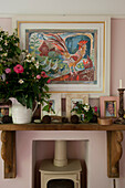 Wooden mantlepiece with artwork and cut flowers with wood burning stove in contemporary Lewes home,  East Sussex,  England,  UK