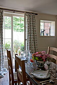 Wooden dining table and chairs with view to garden from Ashford home,  Kent,  England,  UK