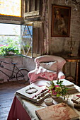 Pink armchair with bicycle at open window in living room of stone farmhouse,  Dordogne,  France