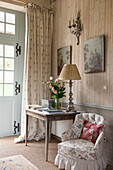 Upholstered chair and table with lamp and door curtain in Dordogne cottage hallway  Perigueux  France