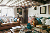 Blue and white cushions on brown leather sofas with beamed ceiling in Ashford living room  Kent  UK