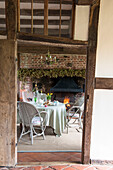 View through modernised timber framed doorway to table at brick fireside in High Halden cottage  Kent  England  UK