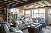 Bücherregale und Sitzgelegenheiten unter der Balkendecke im Wohnzimmer von High Halden mit Bleiglasfenstern, Kent, England, Vereinigtes Königreich