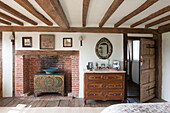 Wooden chest of drawers and recessed  brick fireplace in beamed High Halden cottage  Kent  England  UK