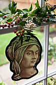 Mistelblätter und Beeren mit Buntglasfigur im Fenster des Londoner Hauses England UK