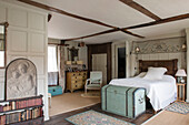 Embroidered fabric above double bed with travelling trunk in Suffolk home  England  UK