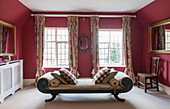 Antique daybed with checked cushions in red bedroom of Suffolk farmhouse  England  UK