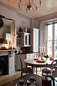 Lit candles on kitchen table with Christmas garlands in North London Victorian house  England  UK