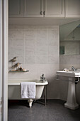 Cream tiled bathroom with high cupboards in North London Victorian house  England  UK