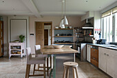Stools at curved breakfast bar in kitchen of Oxfordshire barn conversion  England  UK