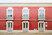 Rot gestrichene Fassade mit Balkonen in Castro Marim, Portugal