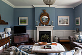 Konvexer Spiegel über Kamin mit TV auf Beistellmöbel in hellblauem Amberley-Wohnzimmer in West Sussex England UK