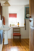 Chair at window with pedestal basin in Devon bathroom England UK