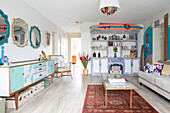 Surfboard and ornaments on up-cycled cabinets in renovated 1950s coastal beach house West Sussex UK
