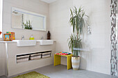 Double basins with under sink storage and large houseplant in renovated 1950s coastal beach house West Sussex UK