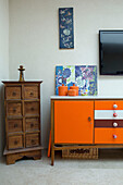 Upcycled sideboard and wooden chest with TV and artwork in beach house West Sussex UK