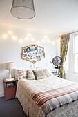 Gilt framed vintage mirror above double bed with tartan checked blanket in London family home,  England,  UK
