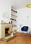 Black leather chair on parquet floor with tiled fireplace in London family home  England  UK