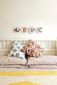 Einzelnes Wort 'LOVE' auf dekorativen Tellern über floral gemusterten Kissen im Schlafzimmer eines Hauses in Birmingham England UK