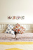 Single word 'LOVE' on decorative plates above floral patterned pillows in bedroom of  Birmingham home  England  UK