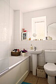 Wicker baskets in white tiled bathroom of Birmingham home  England  UK