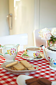 Afternoon tea with biscuits on red and white table cloth in Faversham home,  Kent,  UK