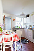 Red and white checked tablecloth in fitted kitchen of Faversham home,  Kent,  UK