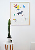Modern art and cactus on side stool in London home  UK