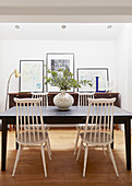 Leaf arrangement on table with white dining chairs in London home  UK