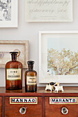 Medicine bottles and artwork above vintage wooden sideboard in London home  UK