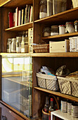 Storage jars and books on wooden shelving with glass  panel in West Yorkshire kitchen  UK