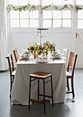 Gedeckter Esstisch mit langer Tischdecke und Blumen in einem Londoner Haus UK